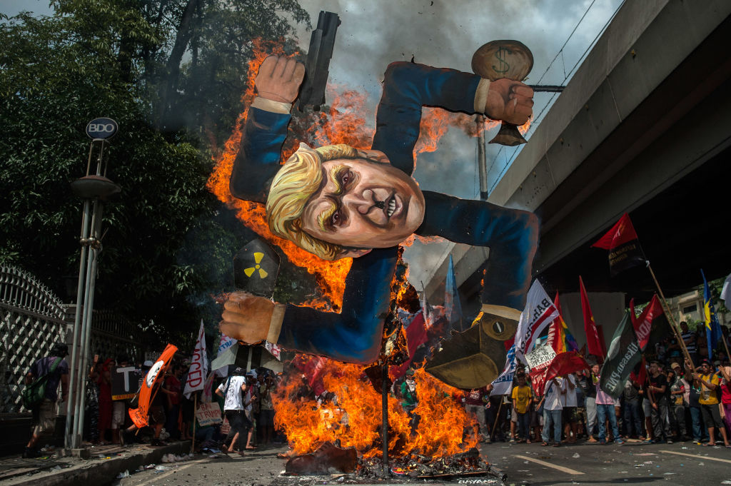 protesters burn an image of trump on a swastika