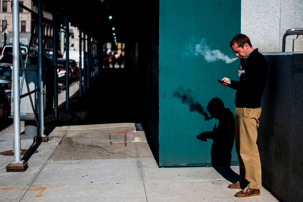 Man smoking on a sidewalk.