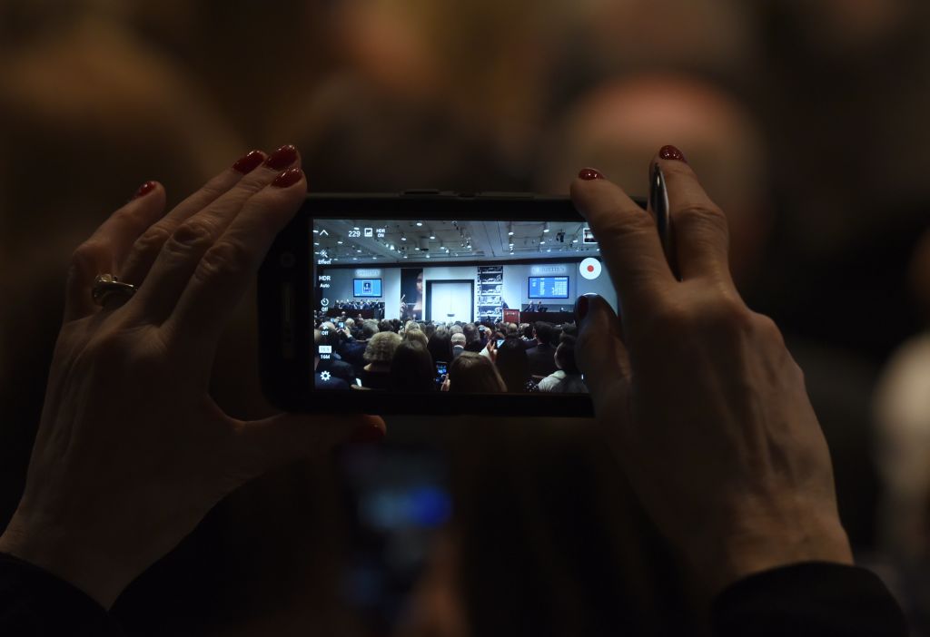 a woman takes a video on a cell phone in a darkened room a woman takes a video on a cell phone in a darkened room