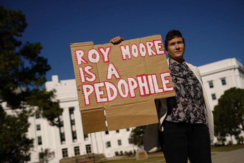 a protester holds a sign against roy moore