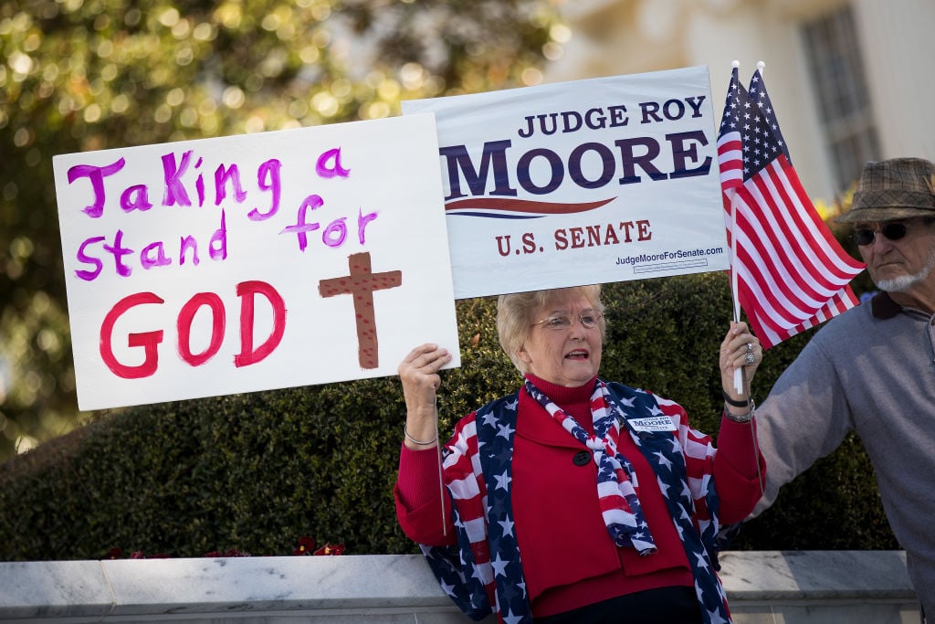 a pro-moore protester holds signs supporting the senate candidate a woman holds pro-moore signs in alabama