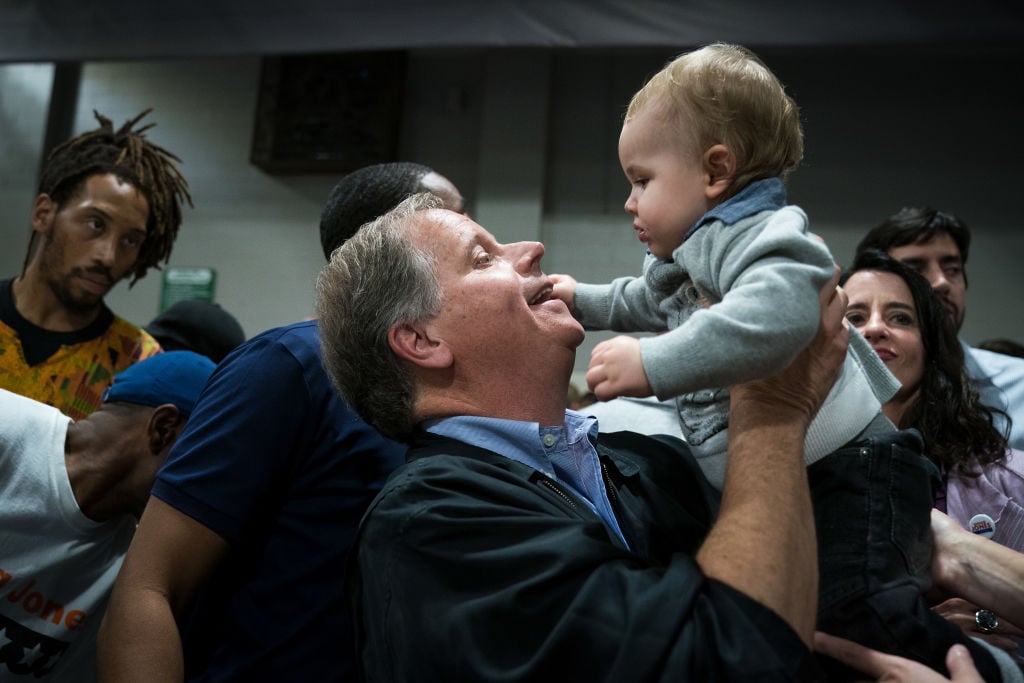doug jones in blue lifting up a baby