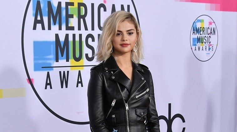 Selena Gomez stands on a red carpet in an edgy leather jacket.