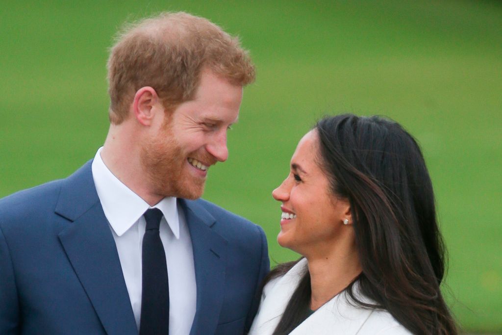 prince harry and meghan markle in a blue suit and white jacket smile at each other prince harry and meghan markle in a blue suit and white jacket smile at each other