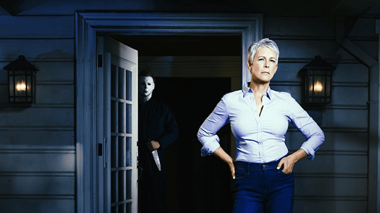 Jamie Lee Curtis stands in front of a dark house. Jamie Lee Curtis stands in front of a dark house.