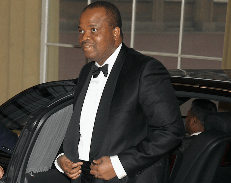 King Mswati III emerging from a black car while wearing a tuxedo. King Mswati III emerging from a black car while wearing a tuxedo.