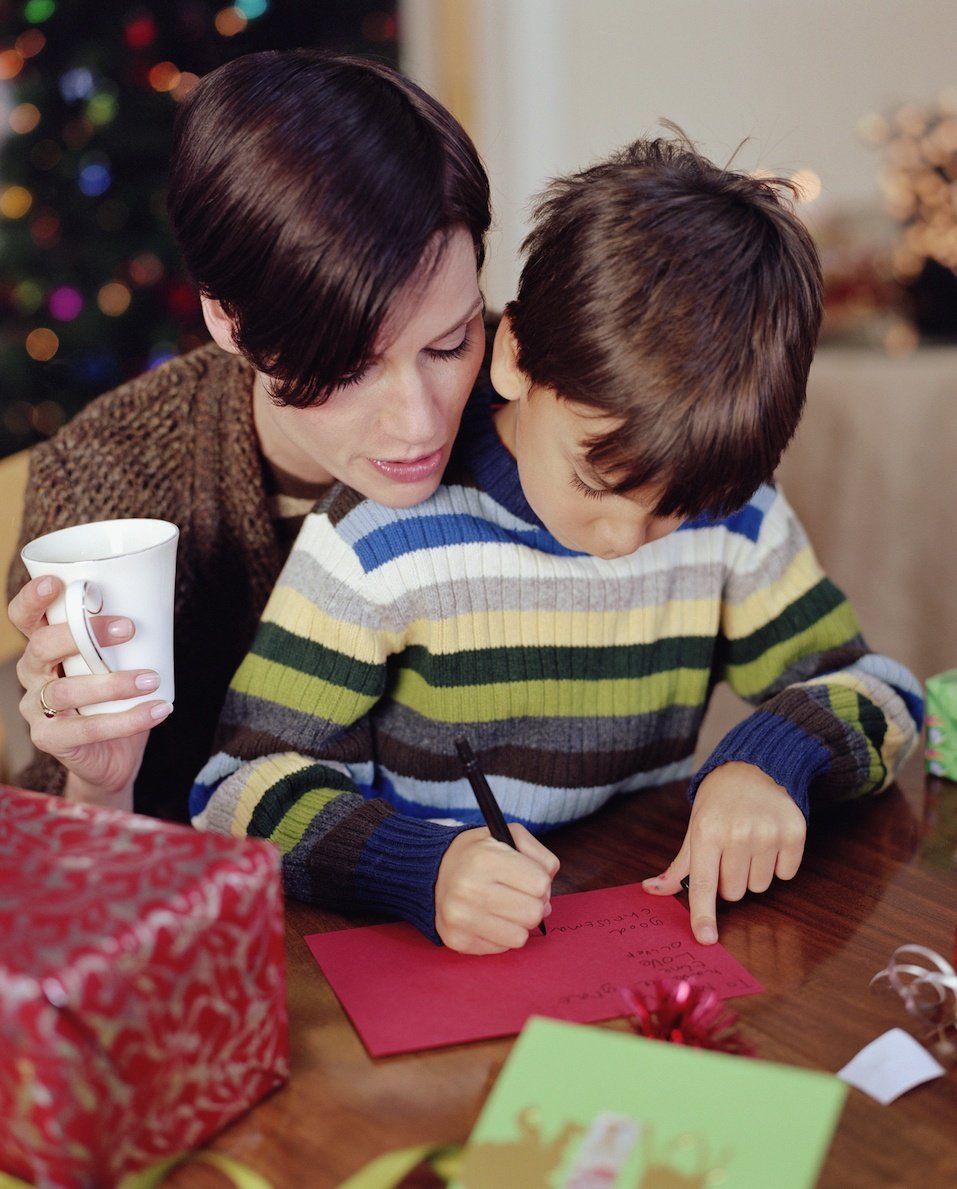 Mother helping son (6-8) write christmas card Mother helping son (6-8) write christmas card