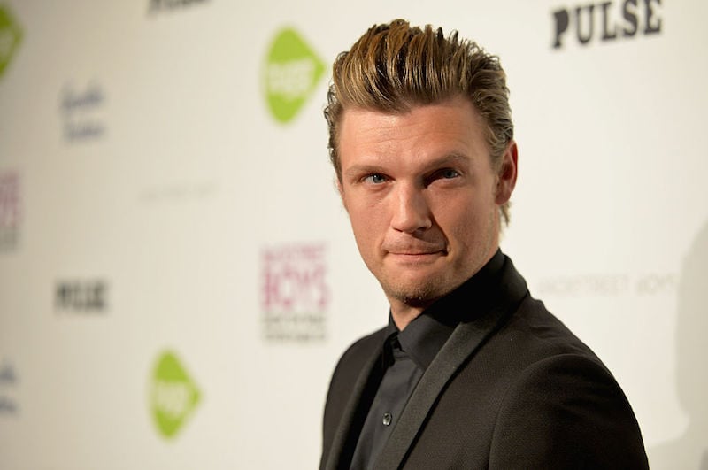 Nick Carter looking towards photographers while posing on a red carpet.