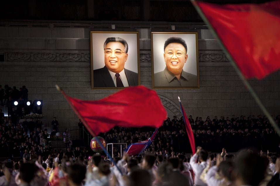 North Koreans wave flags in front of portraits of North Korean late president Kim Il-Sung (L) and his son Kim Jung-Il during celebrations