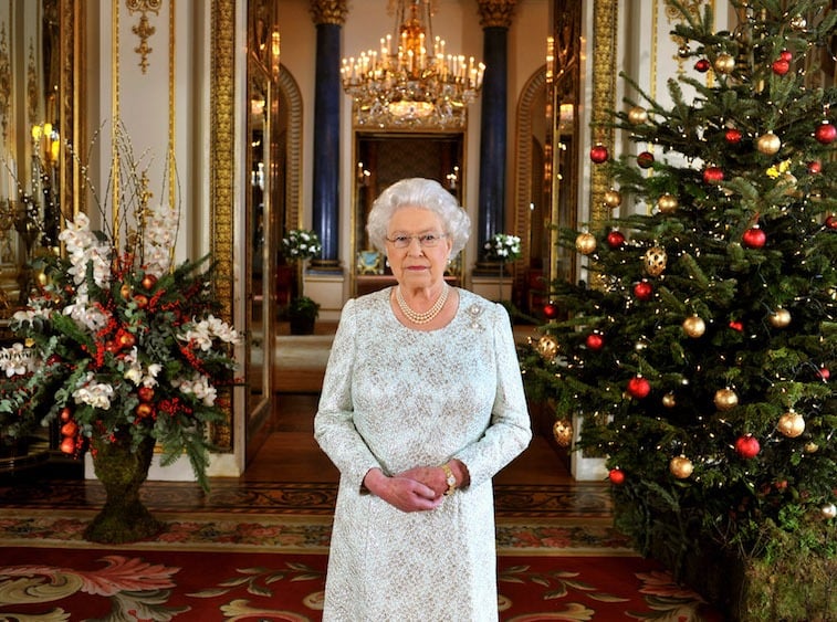 Queen Elizabeth standing between Christmas trees. 