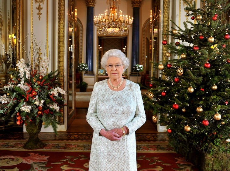 Queen Elizabeth standing between Christmas trees.
