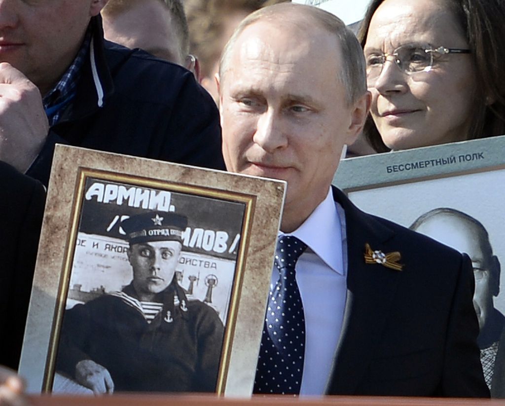 Russian President Vladimir Putin holds a portrait of his father