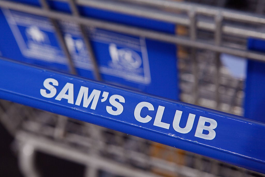 A shopping cart sits in the parking lot of a Sam's Club