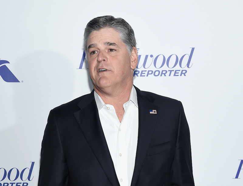 Sean Hannity posing for photographers at a red carpet event. 