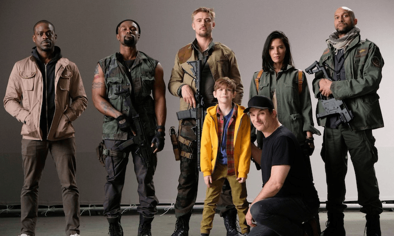 The cast of The Predator holding weapons and standing with a child. The cast of The Predator holding weapons and standing with a child.