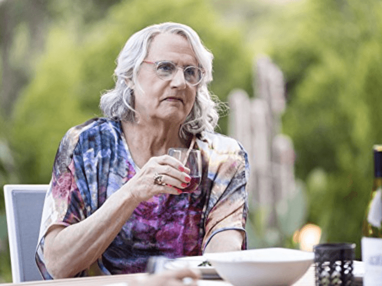 Maura holding up a glass at an outdoor table. Maura holding up a glass at an outdoor table.