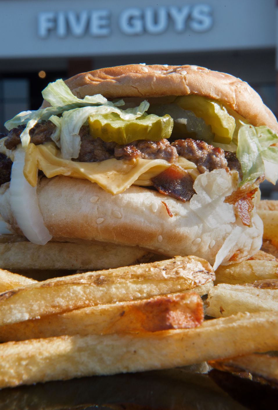 A bacon cheeseburger with French fries is viewed outside the popular Five Guys hamburger chain