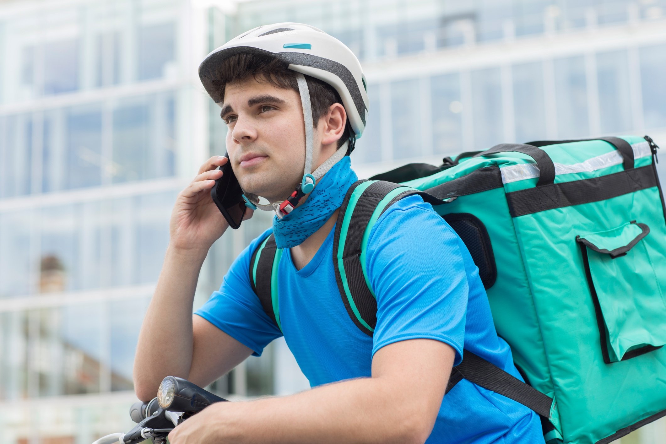 Courier On Bicycle Delivering Food In City Using Mobile Phone