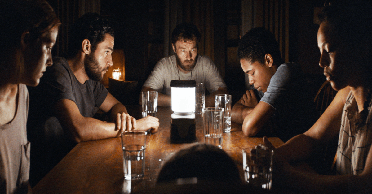 A group of people sitting around a table in the dark A group of people sitting around a table in the dark