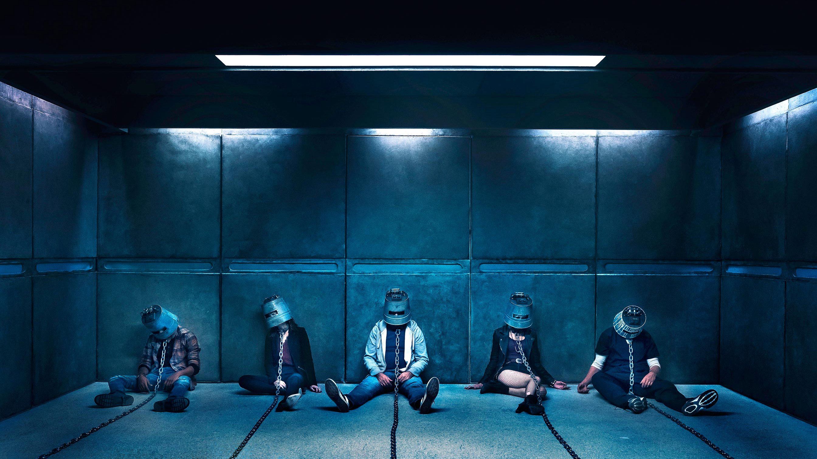 Five people wearing helmets and chains sit in a cell. Five people wearing helmets and chains sit in a cell.