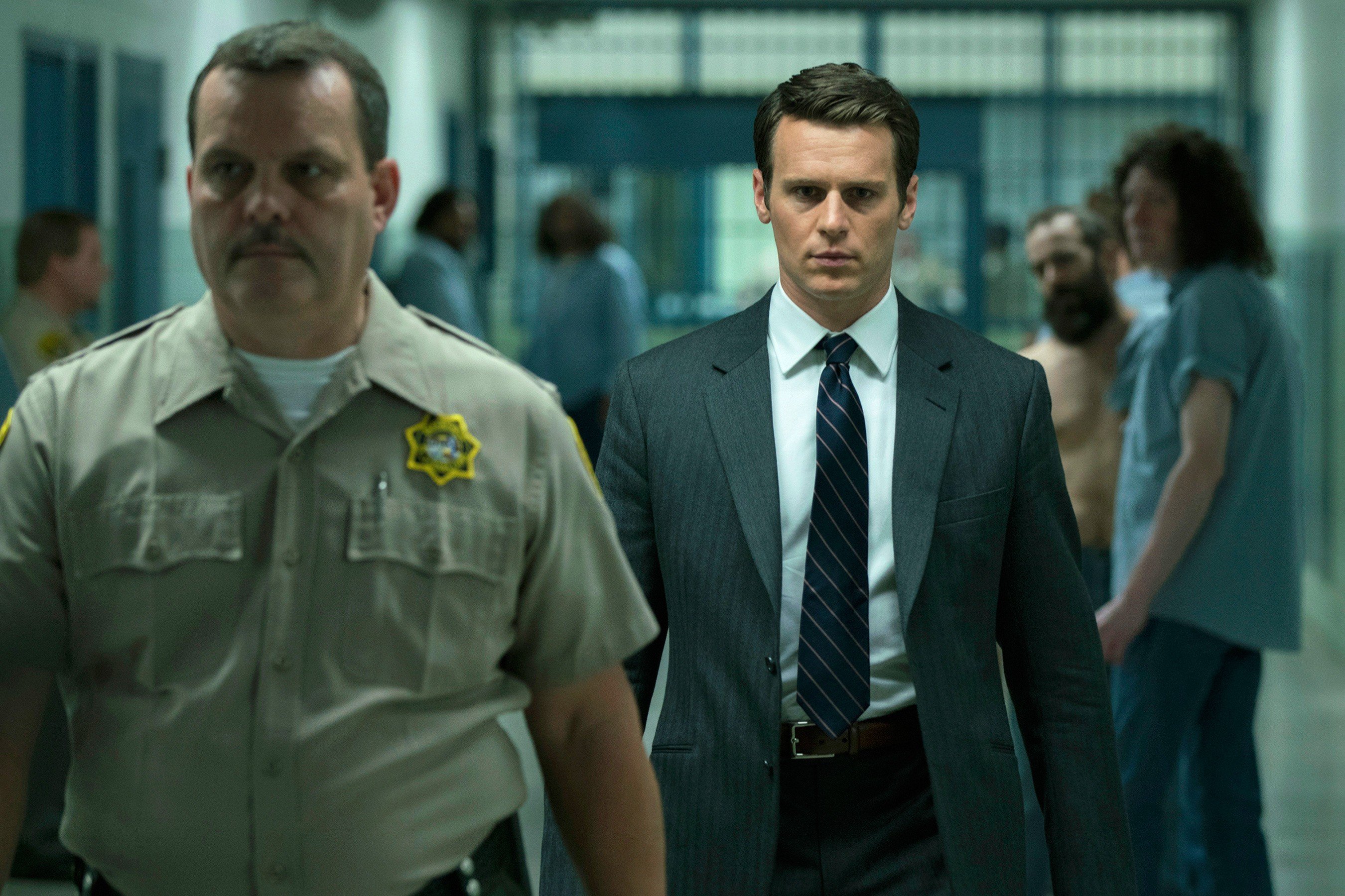 A man in a suit walks behind a security guard A man in a suit walks behind a security guard