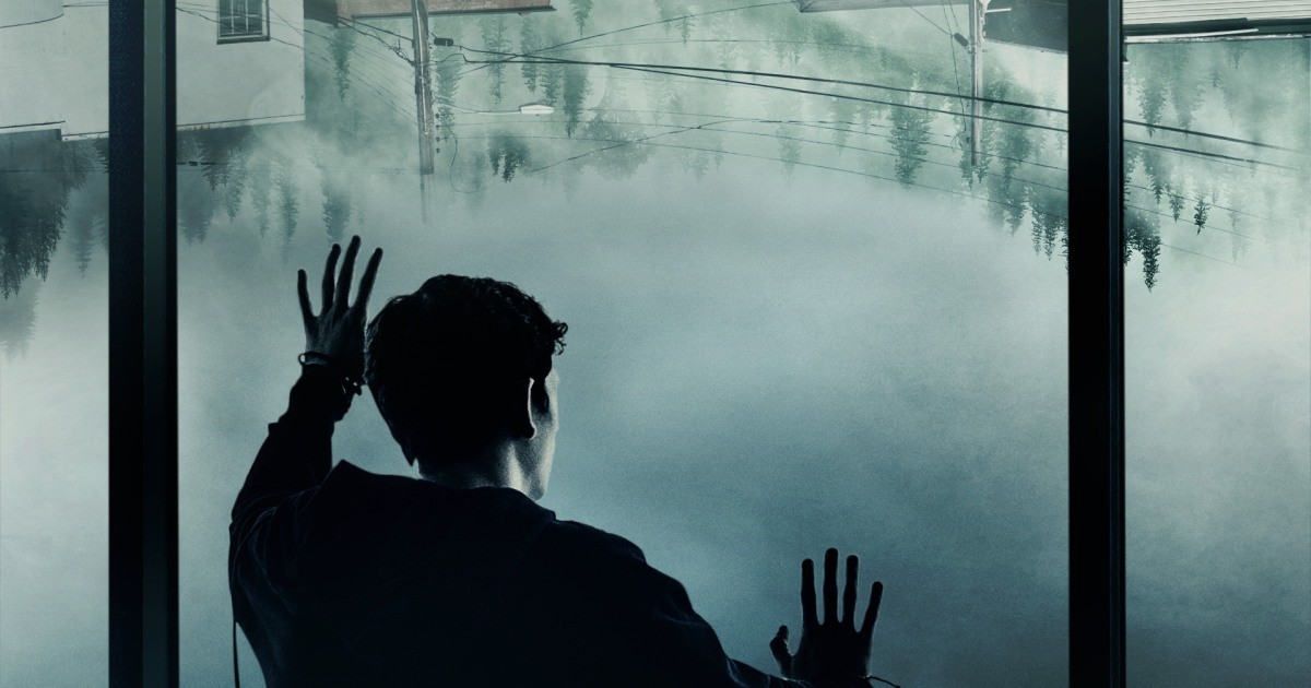 The silhouette of a man keeps his hands against a misted window 