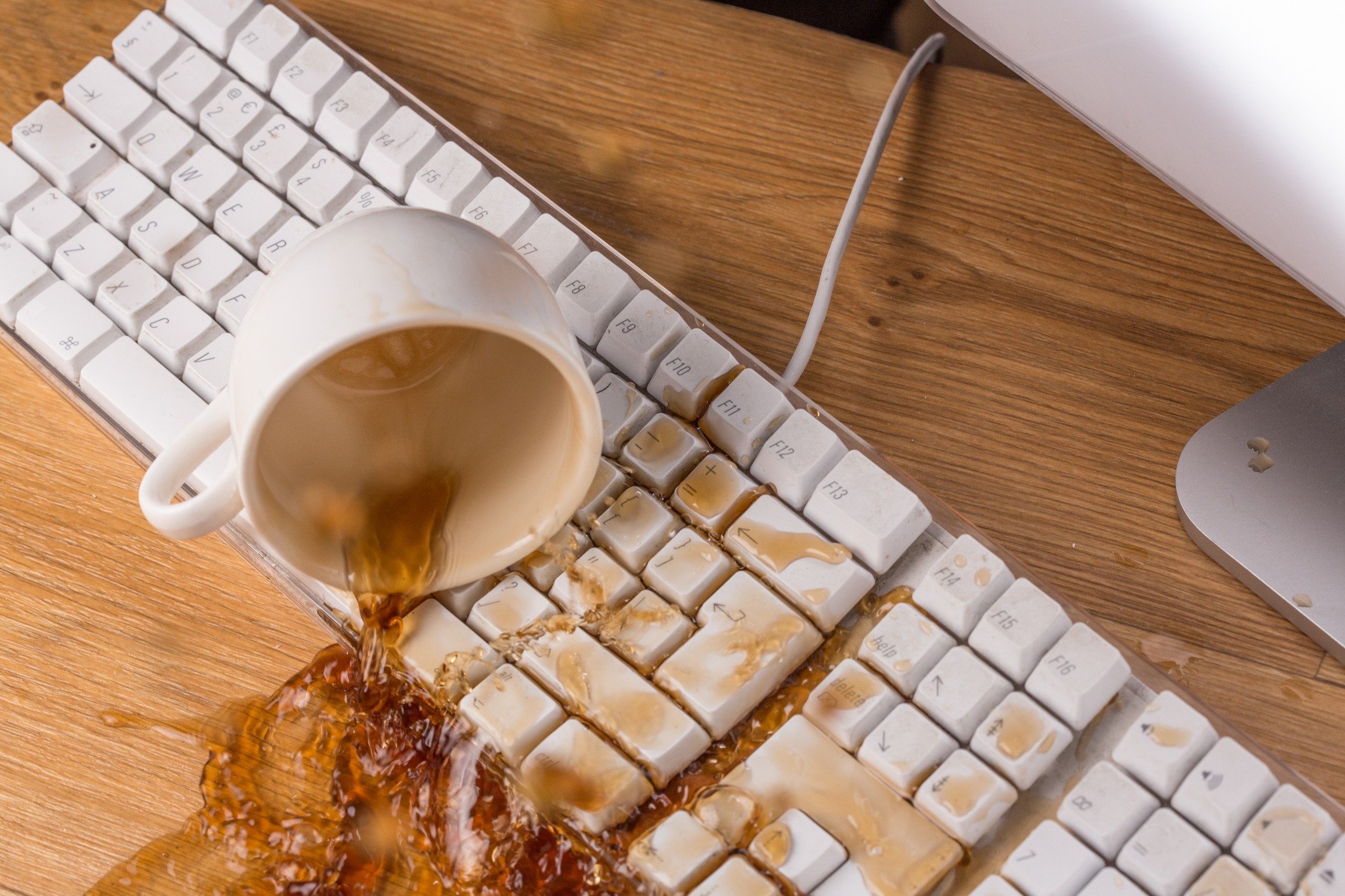 Cup of tea or coffee spilling over a keyboard