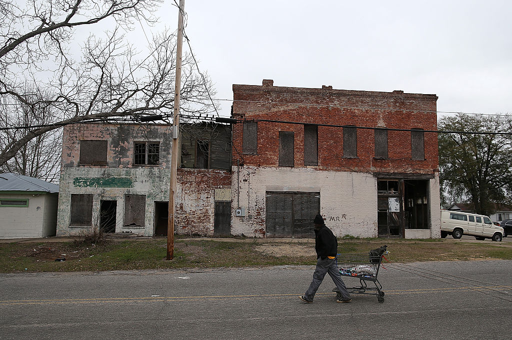 A pedestrian pulls a shopping cart by vacant buildings in Selma, Alabama.