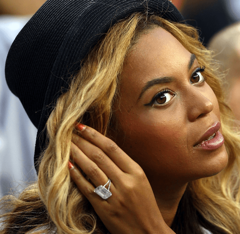 Beyonce adjusting her hair with her left hand at a basketball game. 