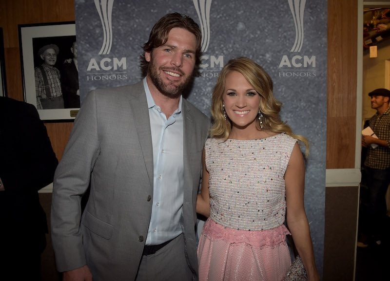 Mike Fisher and Carrie Underwood smile and pose together while holding each other. 