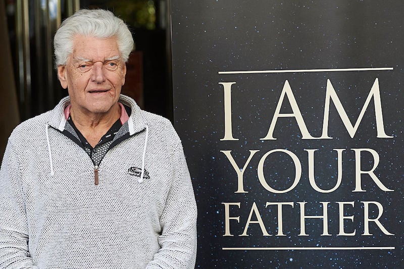 David Prowse posing next to a sign. 