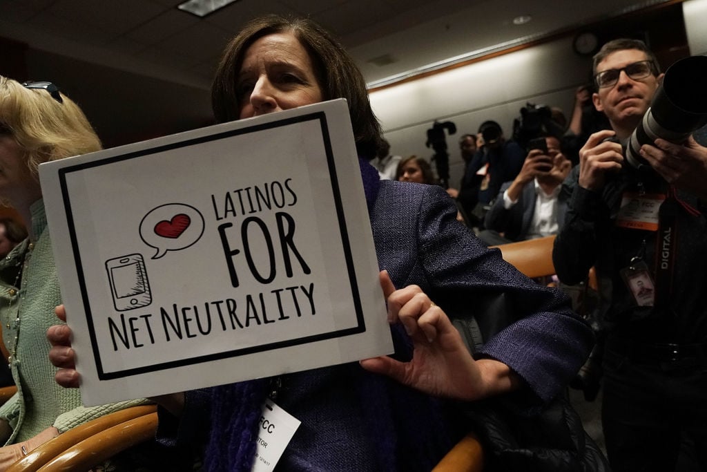 A protester holds a sign during a Federal Communications Commission meeting