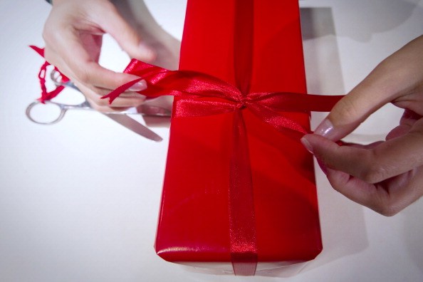 a pair of hands wrap a red present with red ribbon a pair of hands wrap a red present with red ribbon