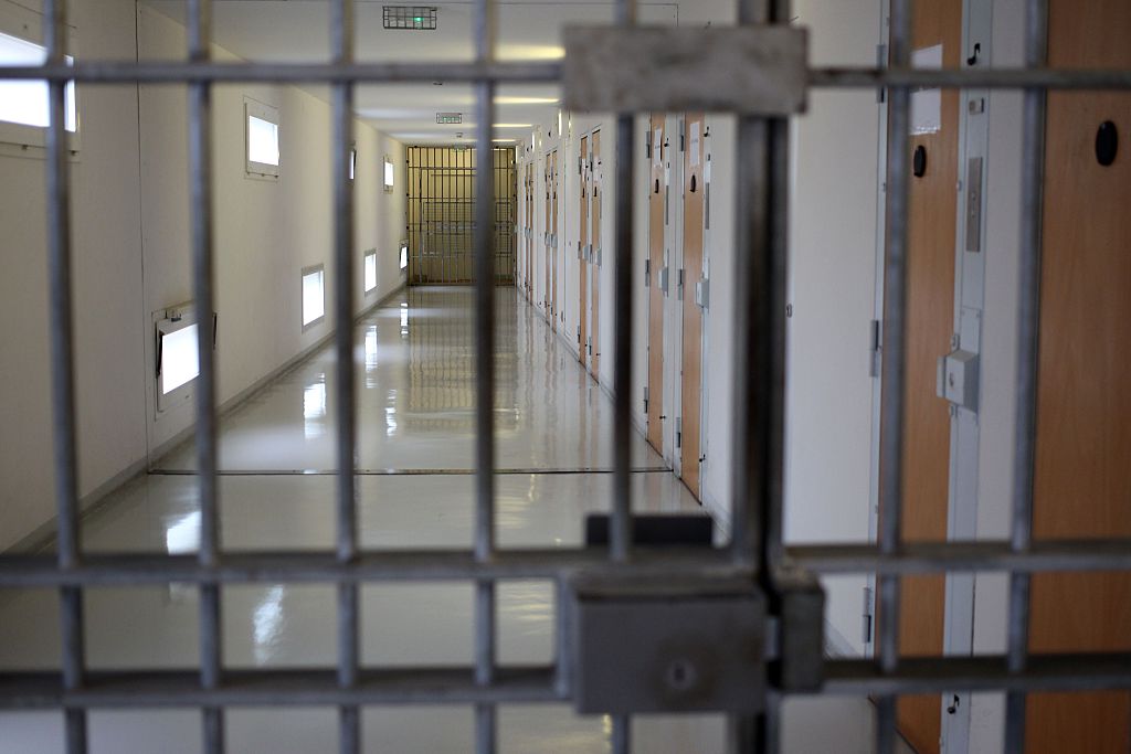 the bars of a jail cell looking down the hallway