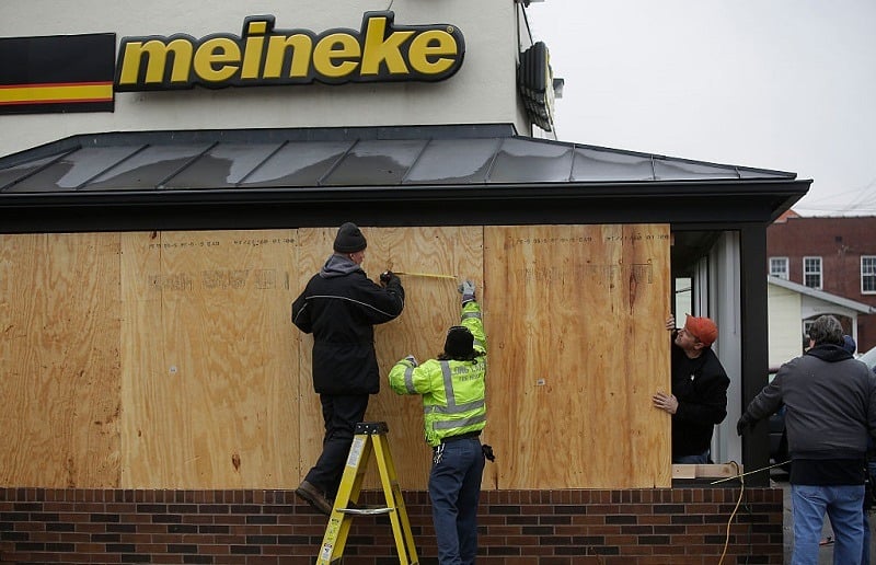 Workers board up windows at a Meineke auto repair shop after demonstrators protesting the shooting death of Michael Brown smashed the windows November 26, 2014 in Ferguson, Missouri. Brown, an 18 year old black male teenager, was fatally shot by Darren Wilson, a white Ferguson Police officer, on August 9, 2014. A St. Louis County 12 member grand jury who reviewed evidence related to the shooting decided not to indict Wilson with charges, sparking riots in Ferguson.