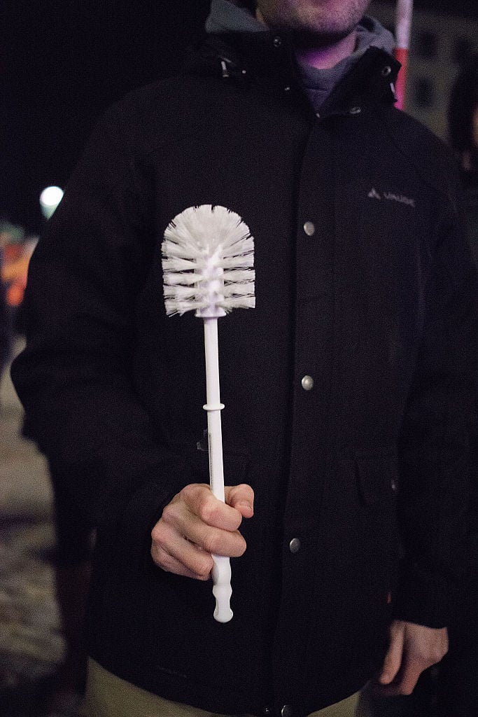 a man holds a white toilet brush a man holds a white toilet brush