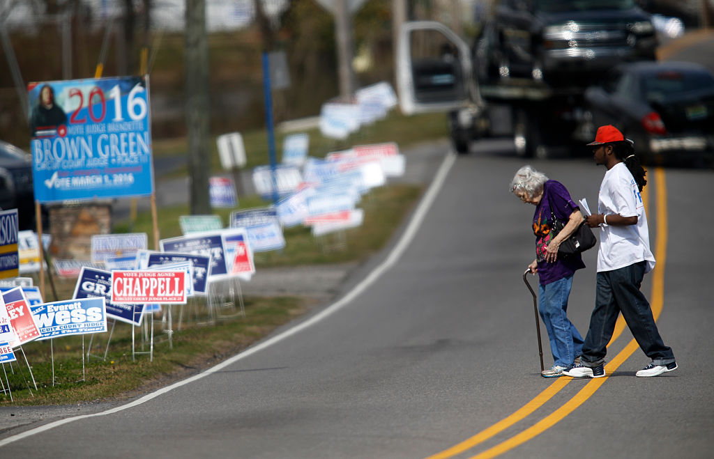 a man helps a woman cross the street to her polling place a man helps a woman cross the street to her polling place