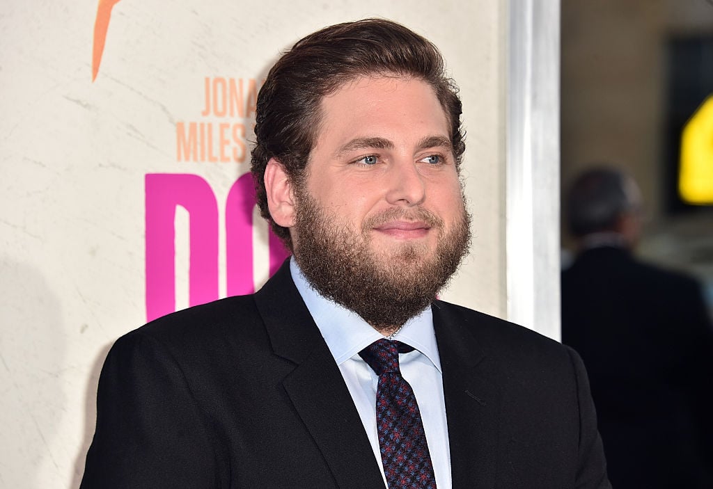 Jonah Hill standing in a black suit and tie. Jonah Hill standing in a black suit and tie.