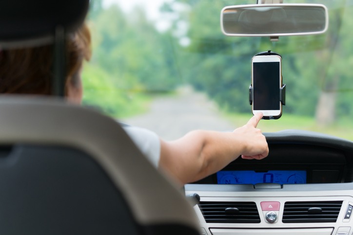 Hand touching screen on smartphone in car