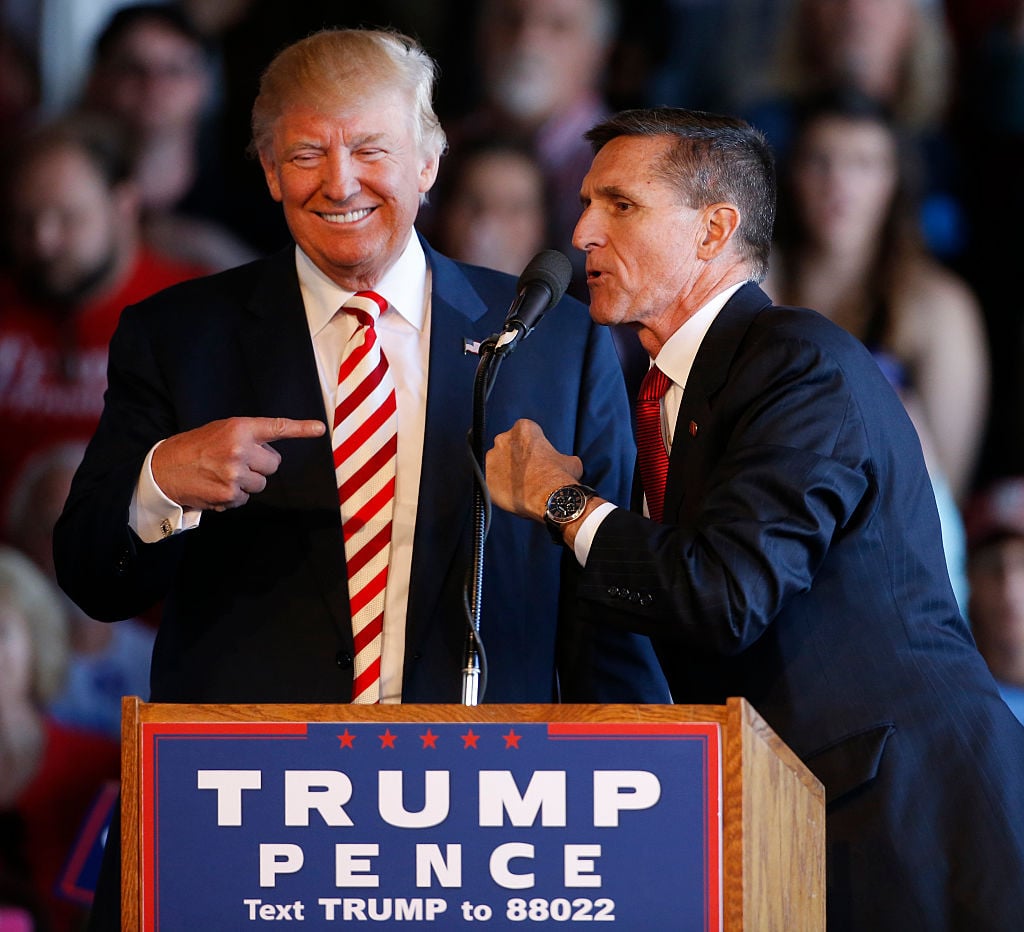 trump and flynn in suits behind a trump campaign sign on a podium trump and flynn in suits behind a trump campaign sign on a podium
