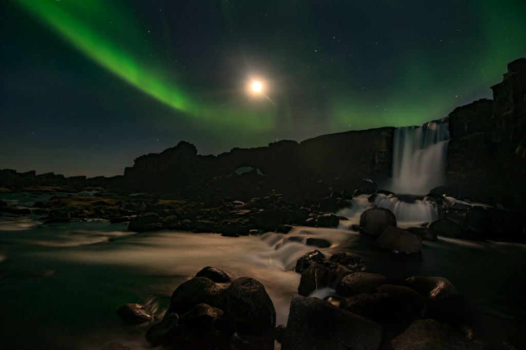 the northern lights above a waterfall at night in iceland the northern lights above a waterfall at night in iceland