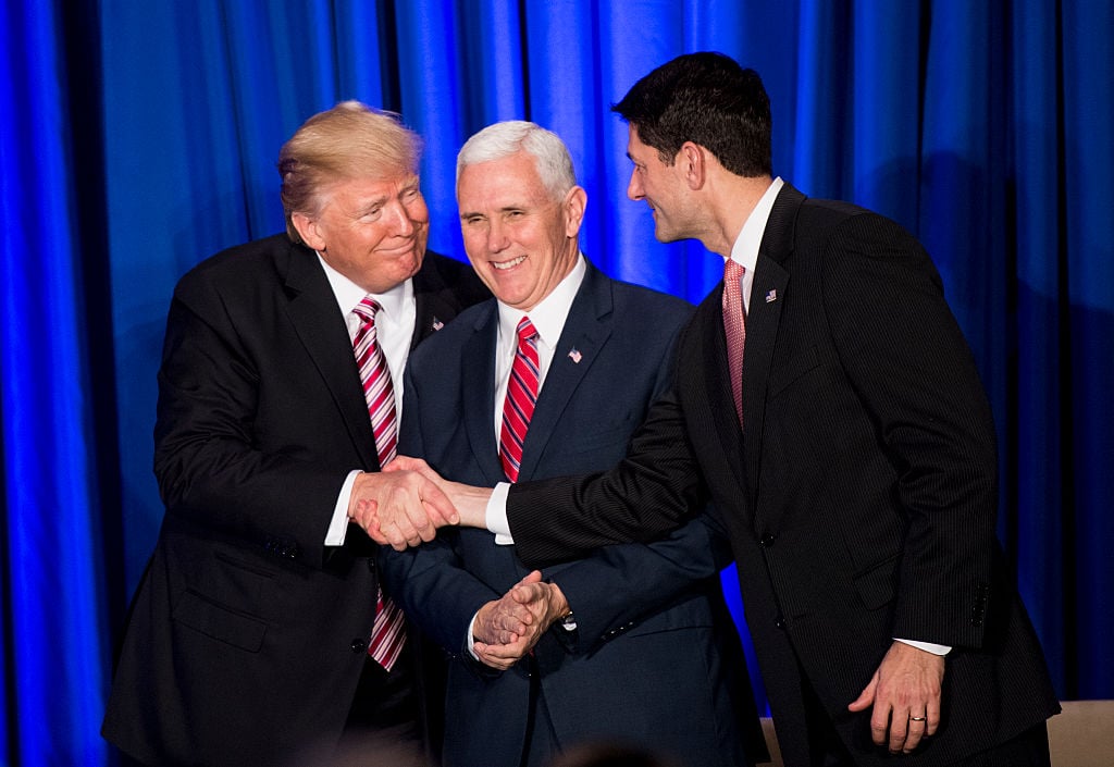 U.S. President Donald Trump shakes hands with Speaker of the House Paul Ryan while Vice President Mike Pence looks on.