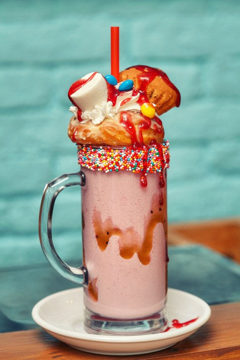Caramel marshmallow candy milk shake cocktail with whipped cream, cookies, waffles and other treats