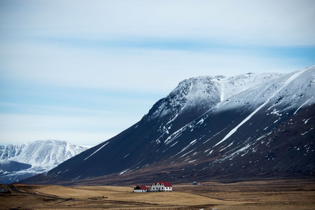 a mountain over a plain with a small house in iceland a mountain over a plain with a small house in iceland