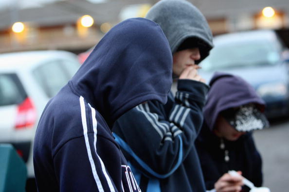 two boys smoking next to cars wearing navy blue hoodies two boys smoking next to cars wearing navy blue hoodies