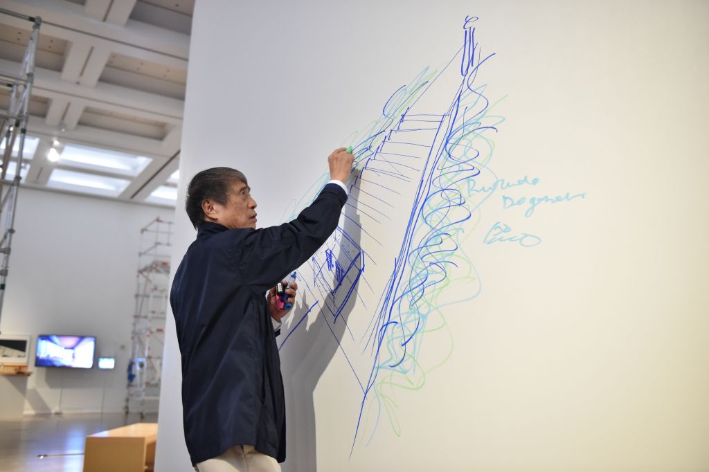 an architect draws with blue marker on a large white piece of paper in an artspace in japan an architect draws with blue marker on a large white piece of paper in an artspace in japan
