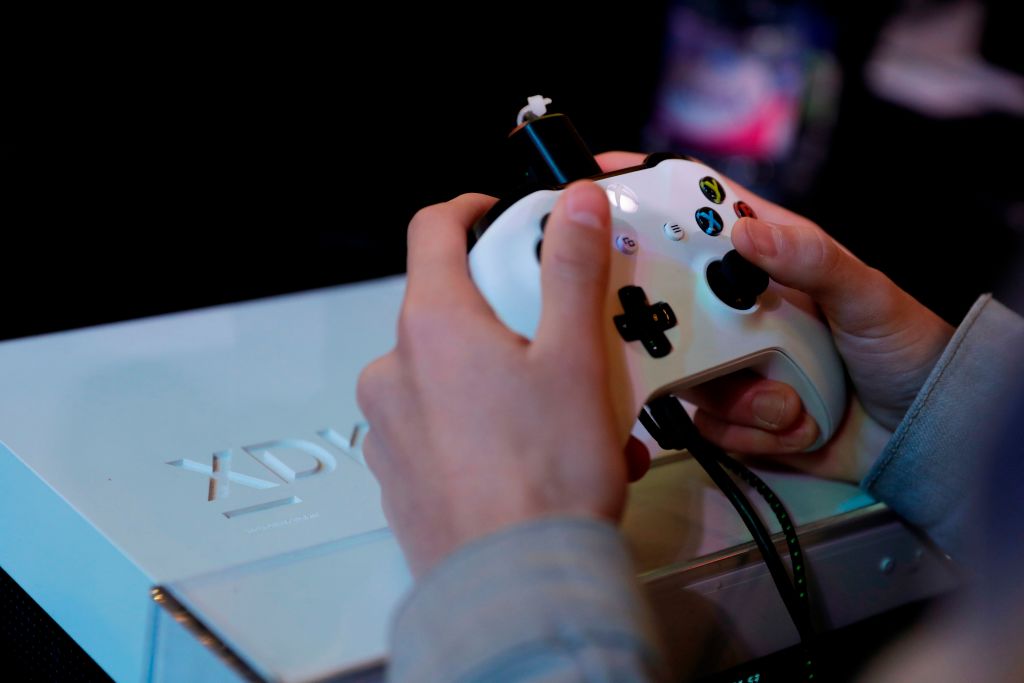 a pair of hands play a white Xbox a pair of hands play a white Xbox