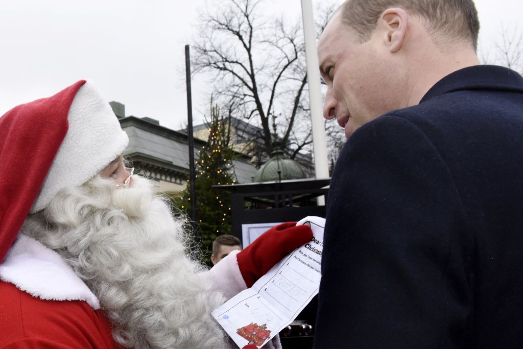 Prince William hands over a wish list by his son Prince George to a person dressed up as Santa Claus as he visits the Esplanade Park and the Manta's Market winter fair in Helsinki, Finland, on November 30, 2017.