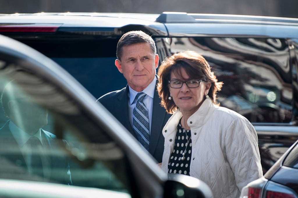 flynn in a dark suit and striped tie behind a car with a woman in white flynn in a dark suit and striped tie behind a car with a woman in white