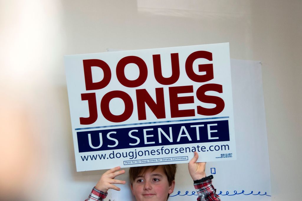 a young boy in plaid holds up a doug jones sign a young boy in plaid holds up a doug jones sign